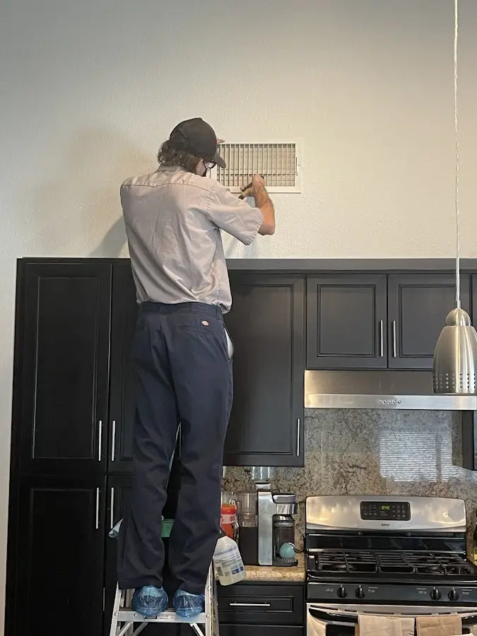 Technician inspecting an air vent during HVAC service in Lafayette